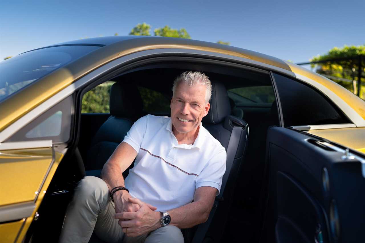 Torsten Müller-Ötvös, the CEO of Rolls-Royce, sits in the front seat of a yellow Rolls-Royce with the door open.