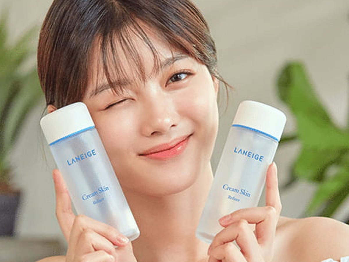 Person winking and holding two bottles of toner.