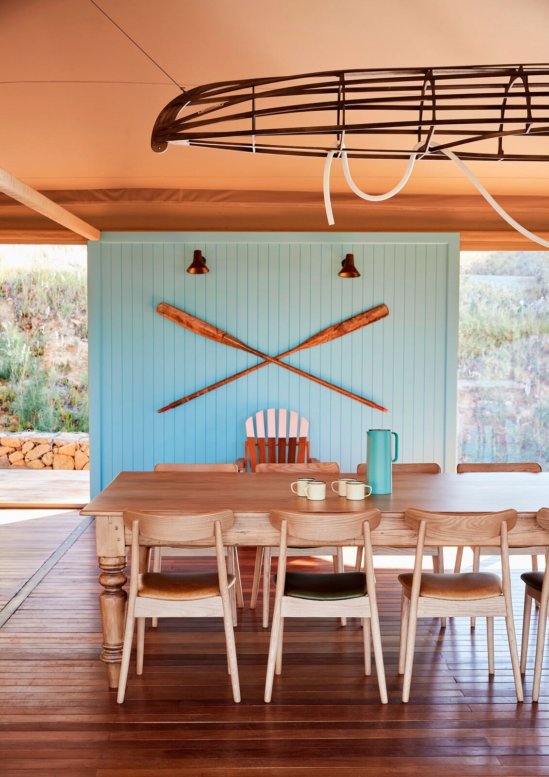 In the central tent, a MADE light strip by Martin Doller is woven through a Barn and Werf canoe frame to create an on-brand light fixture above a large Boschedal dining table. Woodbender chairs offer ample seating for groups.