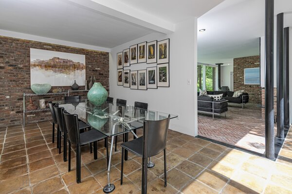 Exposed brick continues throughout the interior, complementing the stone floors and wooden details. The dining area sits between the main living room and kitchen.