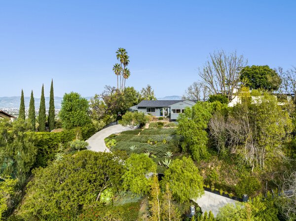 A long gated driveway leads to the perched property, set on a large flat pad measuring over half an acre. The surrounding lush landscaping helps creates a remote city oasis.