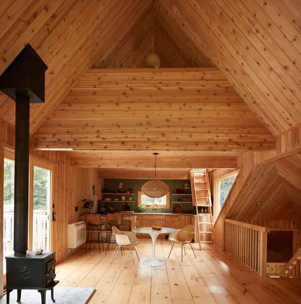 The expansive great room serves as the heart of the home, complete with cedar-paneled cathedral ceilings and glass doors that connect the space to a large adjacent deck.