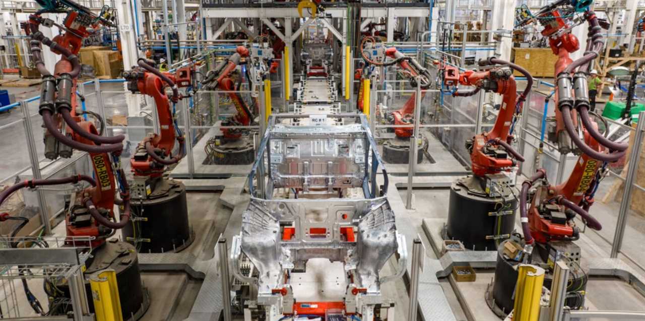 The Tesla Cybertruck production line, with a pickup truck body and several manufacturing robots.