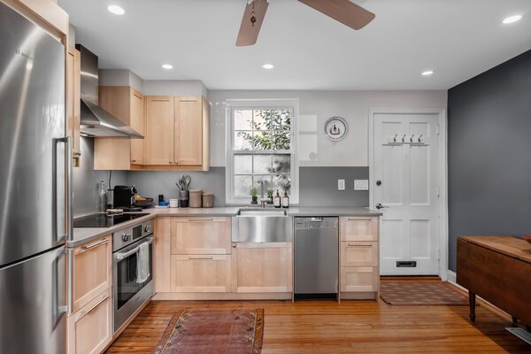 Lined with refinished hardwood floors, the remodeled kitchen presents high-end, stainless-steel appliances, including a Miele dishwasher, Bosch refrigerator, Grohe sink, and Wolf oven. A cozy breakfast nook is built into the opposite side of the room.