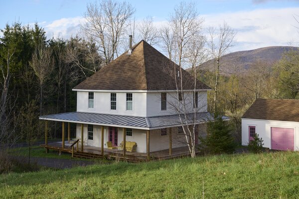 After: A new porch roof, made of metal, completes the updated exterior facade. The home’s doors and the garage door are painted a punchy pink, Benjamin Moore’s Rosewood.