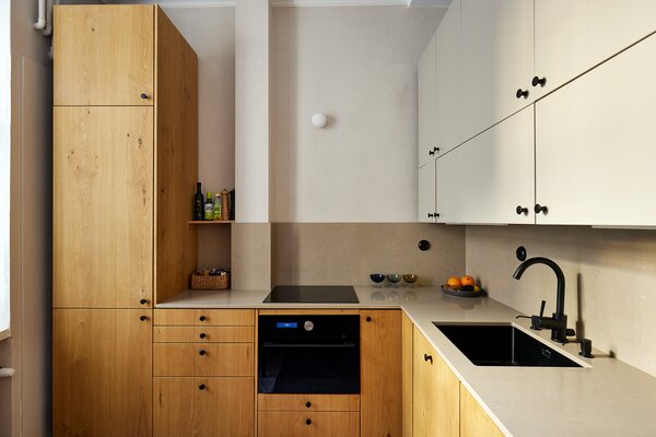 The kitchen sits near the main entry and features long countertops and new appliances. As part of the remodel, the old door recess was converted into cabinets to offer more storage.