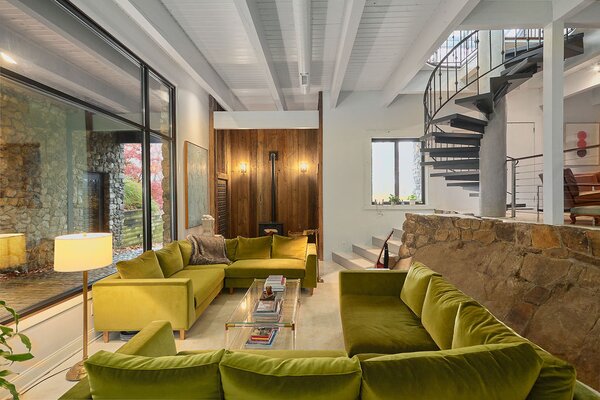 The living room sits adjacent to the main entry, where a glazed wall brings in ample natural light. Original stonework separates the space with the dining area set just steps away.