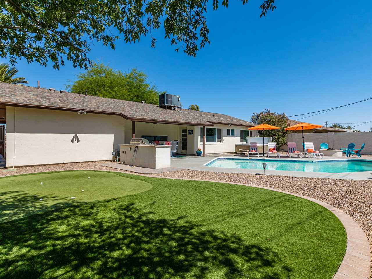 The backyard of one of Gascon's properties with a putting green, pool, and hot tub.