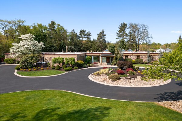 A paved circular drive slices the lush landscaped lot to lead to the stone-clad residence.