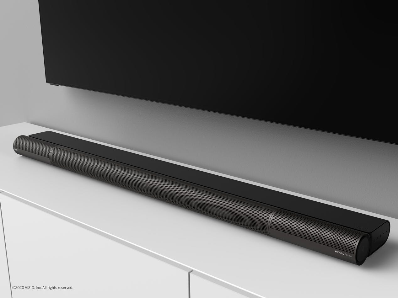 The Vizio Elevate Dolby Atmos soundbar on a TV stand below a TV.