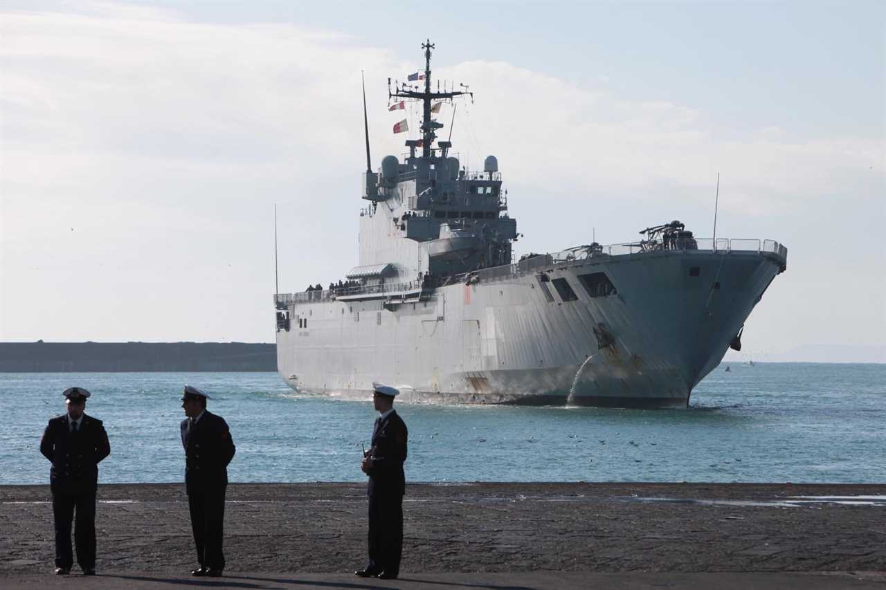 The Italian Navy Ship "San Giorgio" comes to dock with three military officials on land in the foreground