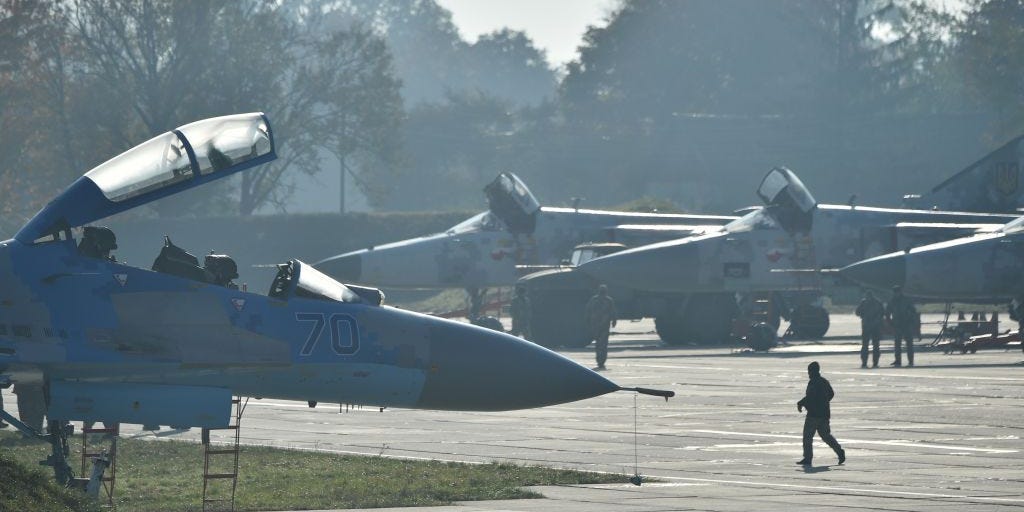 Ukrainian servicemen walk in front of Ukrainian SU-24 and SU-27 military planes during an air force exercises on Starokostyantyniv military airbase on October 12, 2018