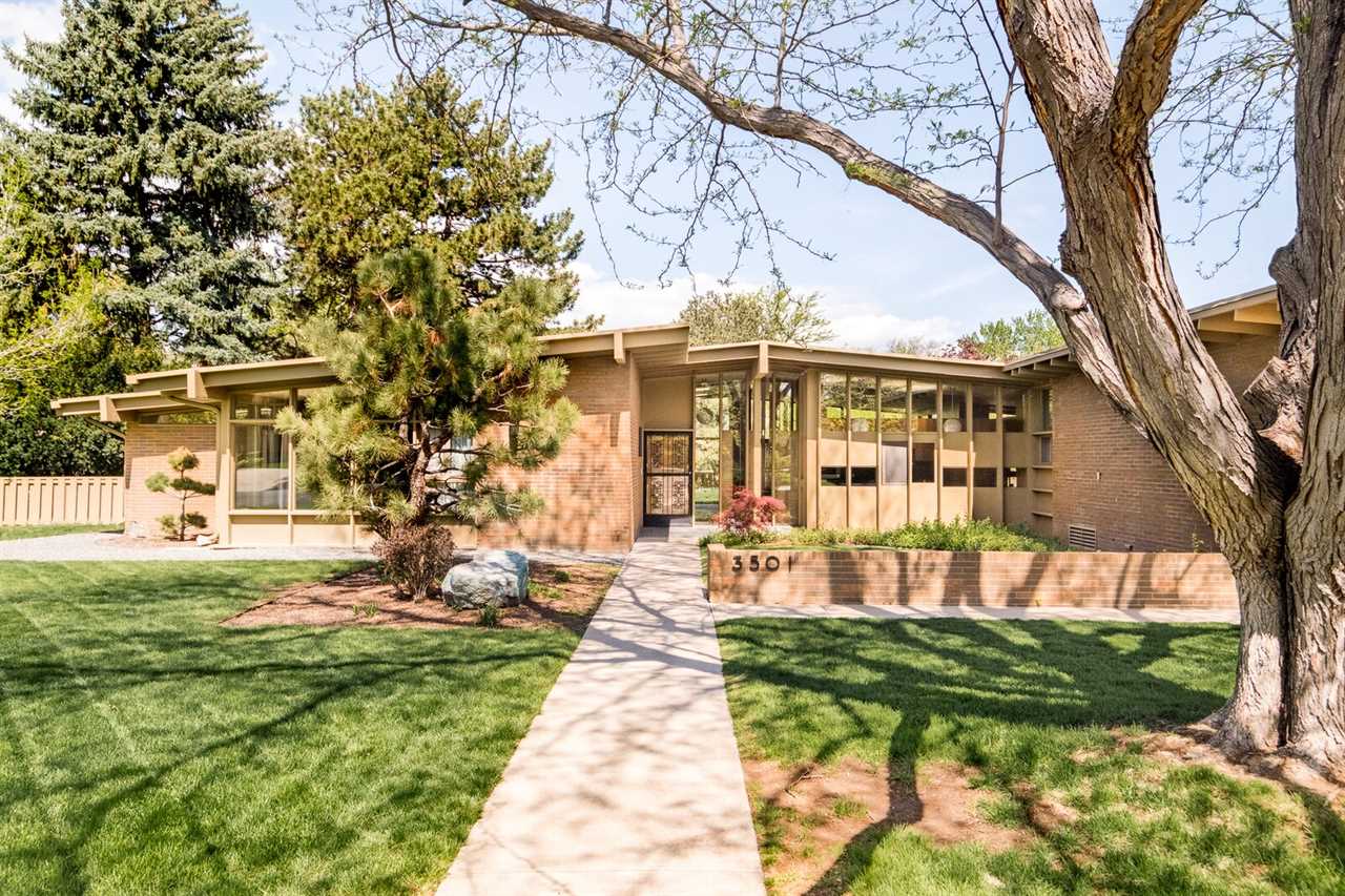 The historic brick home sits on a lush green lawn, peppered with soaring trees and low-maintenance landscaping. Glazed walls allow the backyard to be seen from the main entry.