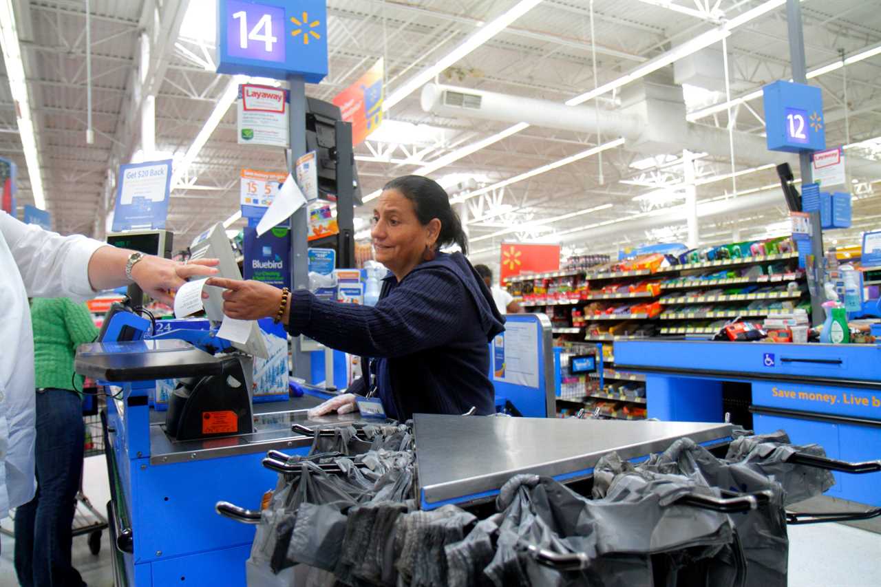 Walmart cashier hands receipt to customer at checkout in Walmart store