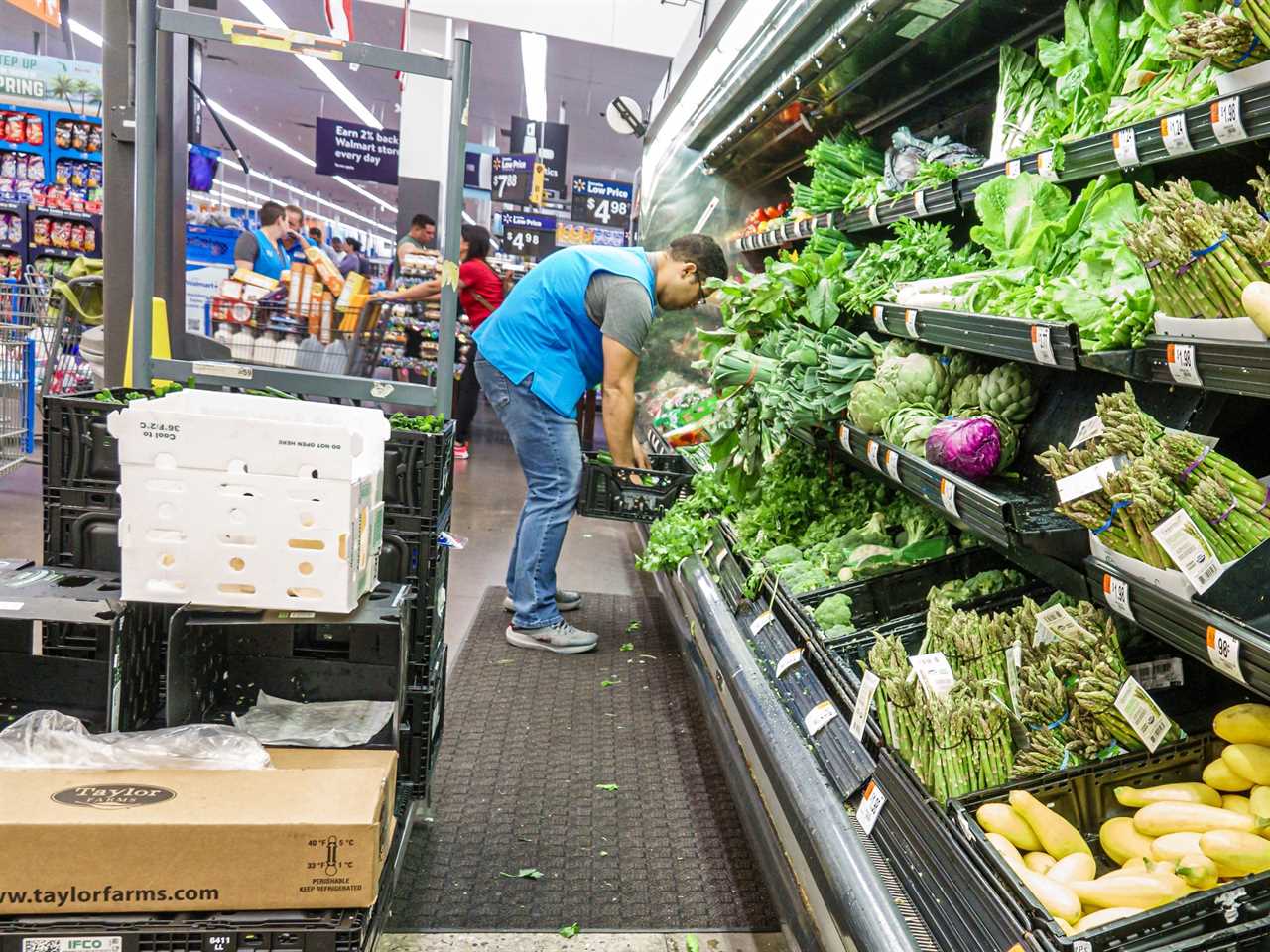 Clerk in a Doral, Florida, Walmart store stocks produce, including greens lettuce and asparagus.