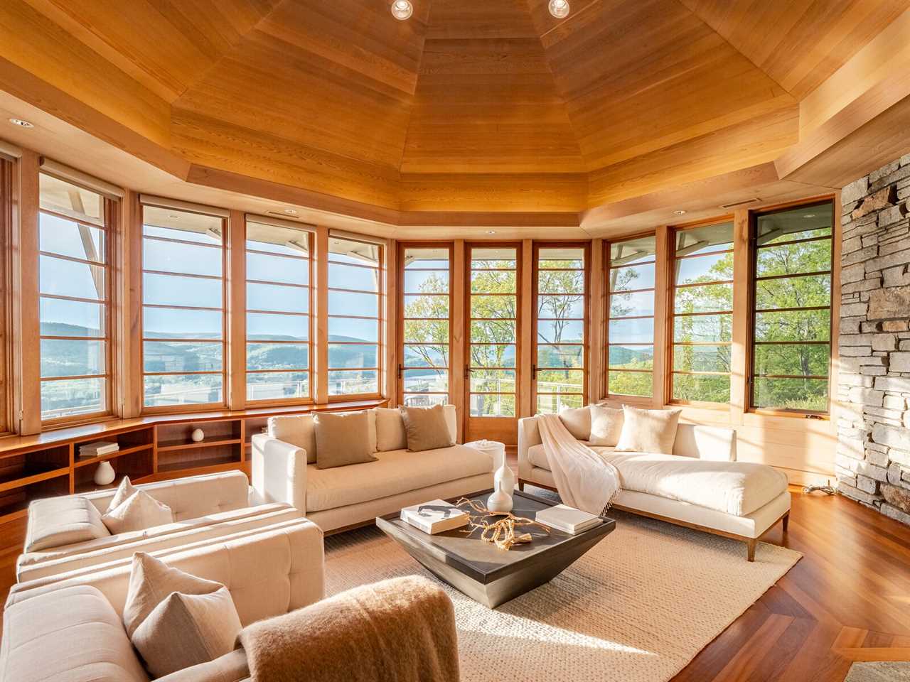 The main living room is lined floor to ceiling with cedar and features a wall of windows overlooking the Hudson River, as well as an custom stone fireplace.