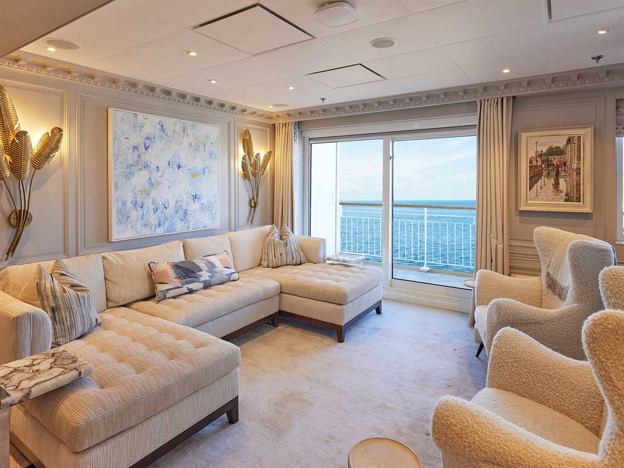 A large seating area with several couches in a white-coloured stateroom inside The World.