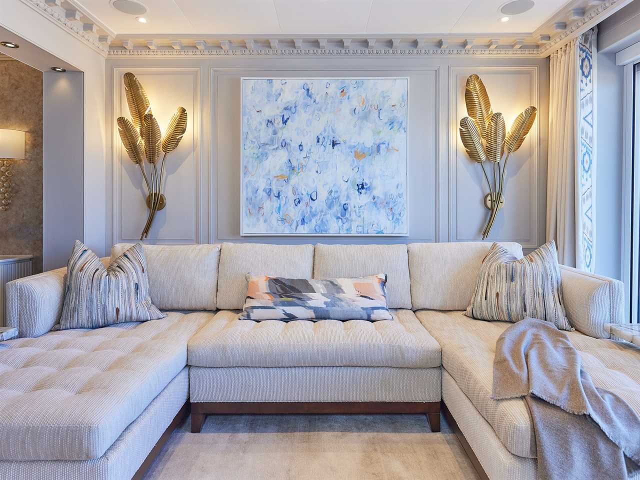 A large white couch inside a stateroom decorated with golden palm leaves.