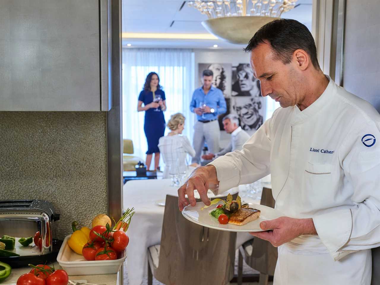 A chef plating up food while two couples talk amongst themselves in a stateroom aboard The World