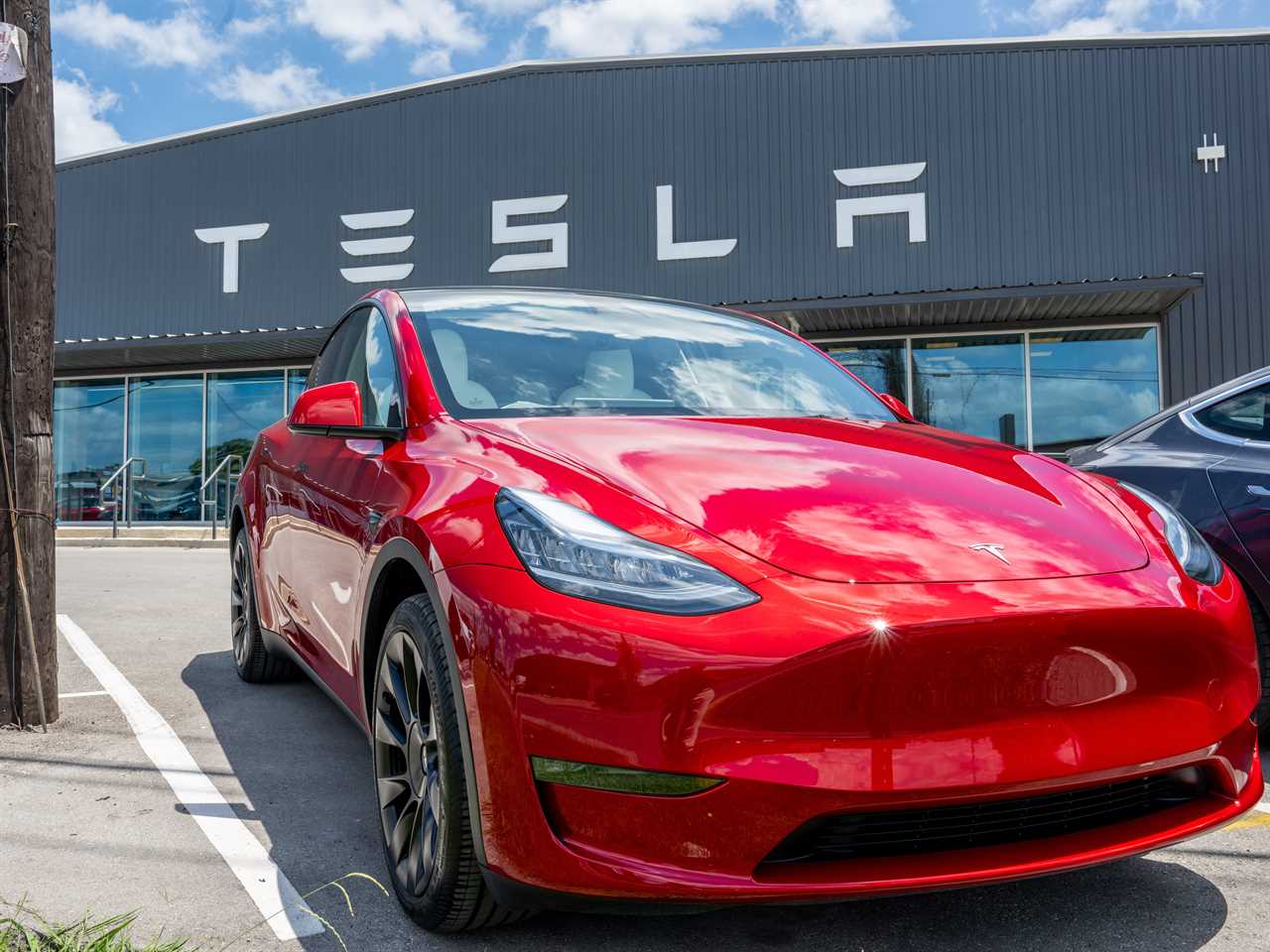 A red Tesla Model Y seen outside a Tesla showroom