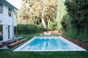 Modern wooden lounge chair next to swimming pool california house