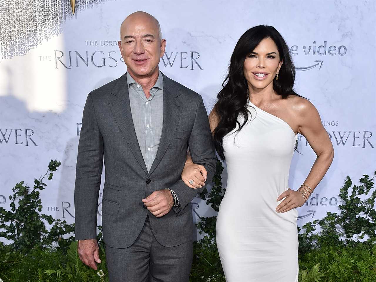 Jeff Bezos wearing a grey suit and Laura Sanchez wearing a white one shoulder dress in 2022