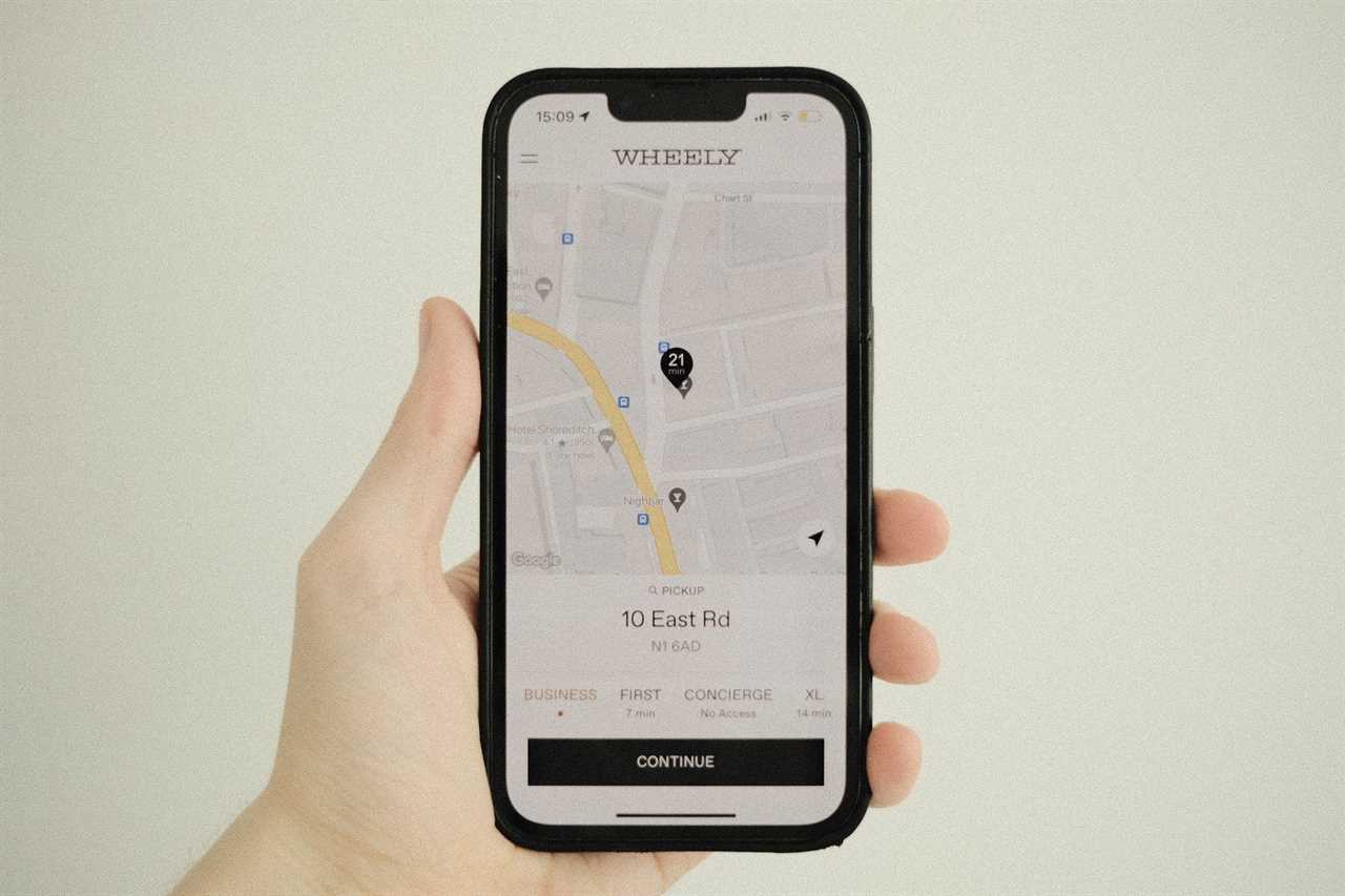 The Wheely ride-hailing app is displayed on an iPhone held in front of a white wall