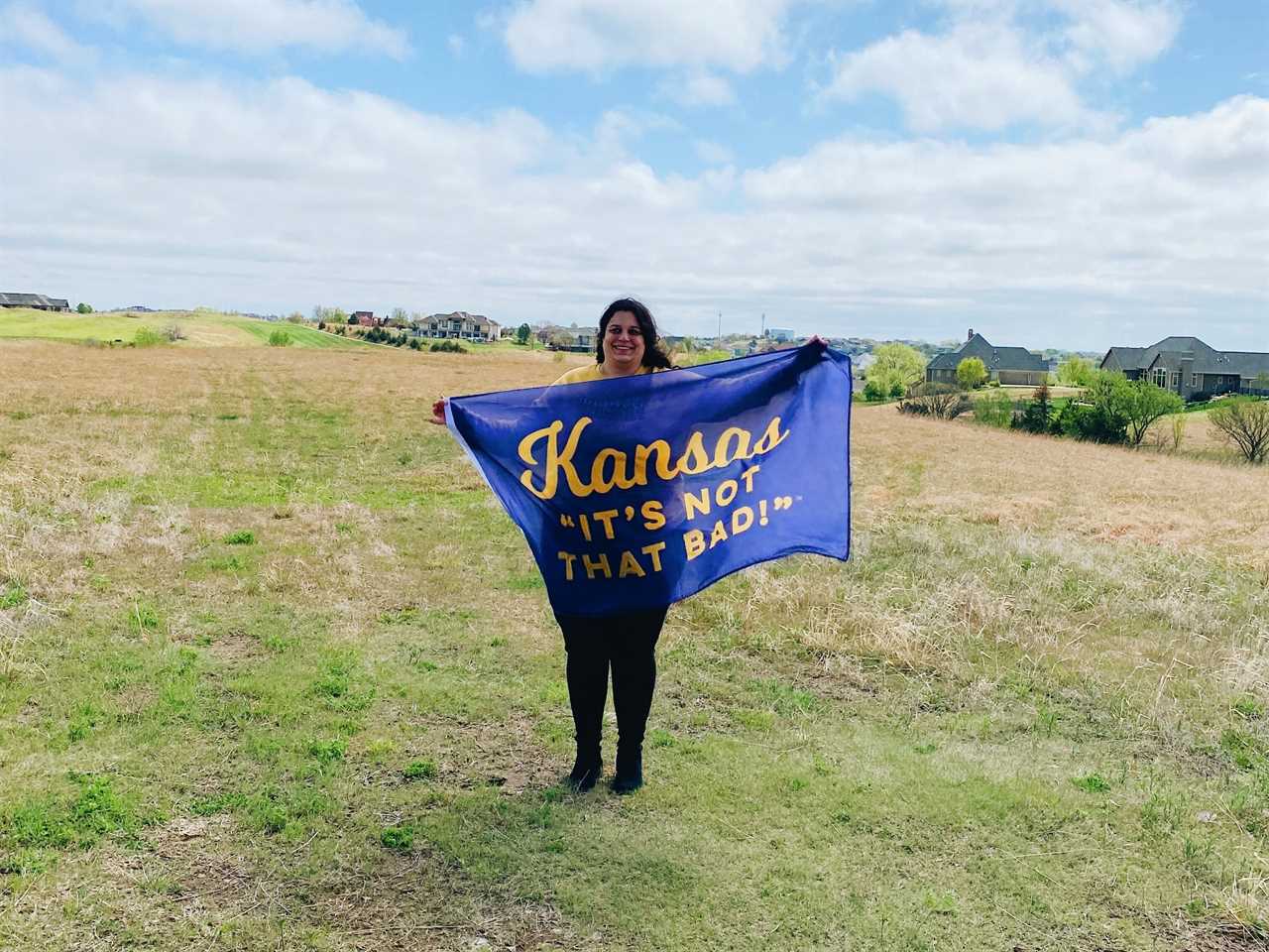 Lauren Savoie holding a sign that says Kansas "It's not that bad"