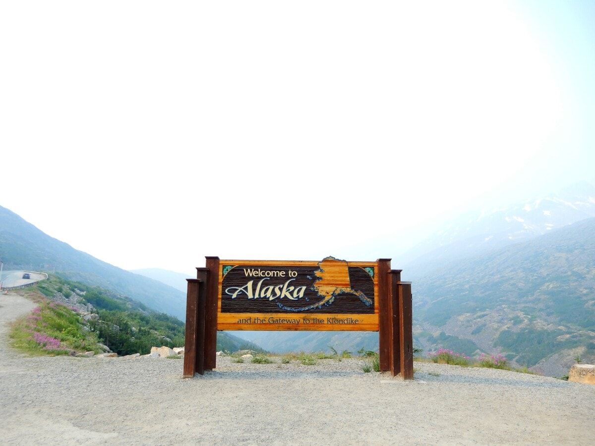 welcome to alaska sign with mountains in back