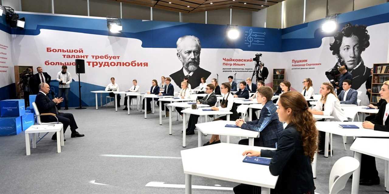 A still from a video of a Q&A session held between President Vladimir Putin and Russian schoolchildren on September 1, 2023, showing a side view of Putin seated, facing multiple youngsters at white school desks.