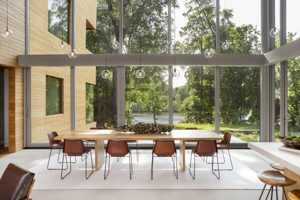 With views of trees, sky, and water, the home’s all-glass living and dining space is enveloped by the landscape.