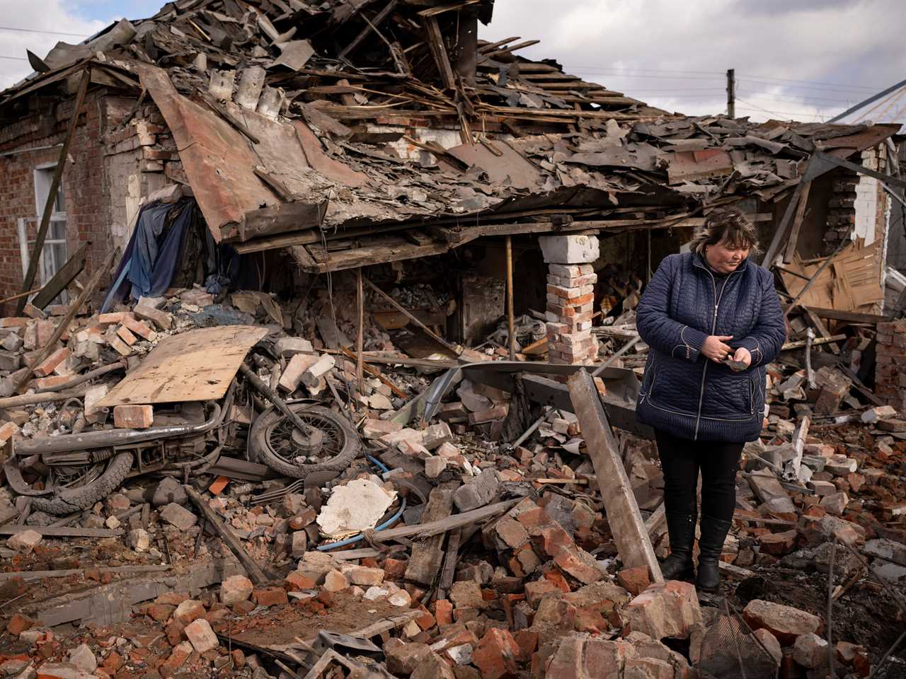 A woman holds a piece of shrapnel standing in the rubble of a house where Ukrainian servicemen were sheltering which destroyed by a Russian S-300 rocket strike, in Kupiansk, Ukraine.