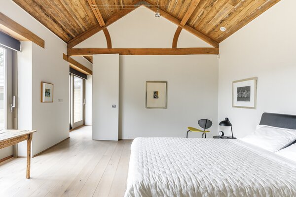 Hand-crafted character oak joinery lines two of the walls in the primary bedroom. Bi-folding doors connect to the large en suite bathroom, where a free-standing tub awaits.