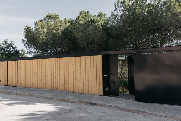 A steel and wood gate-like structure enhances the home’s privacy, keeping it closed from the street and open to the landscape behind the wall.