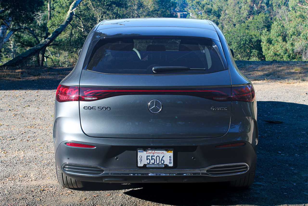 A gray Mercedes-Benz EQE electric SUV in a gravel parking lot. 