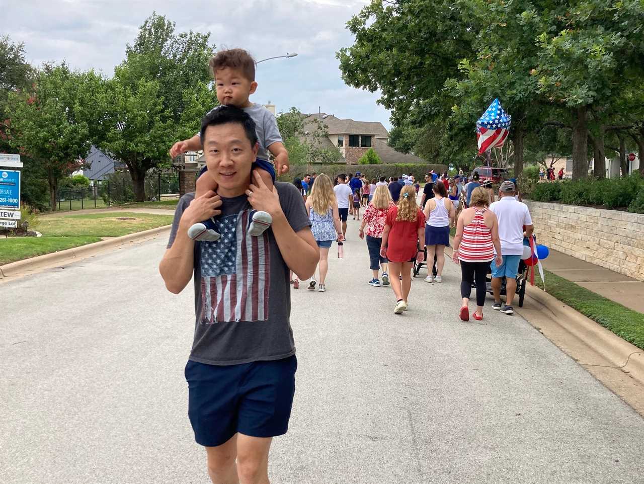 Cheng walking down a path with his son on his shoulders.