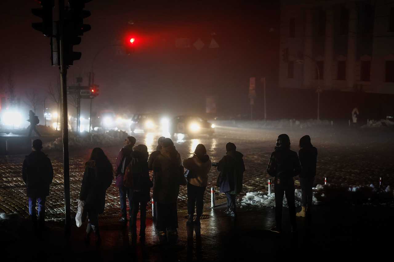 Residents walk through an unlit street following missile strikes in Kyiv, Ukraine.