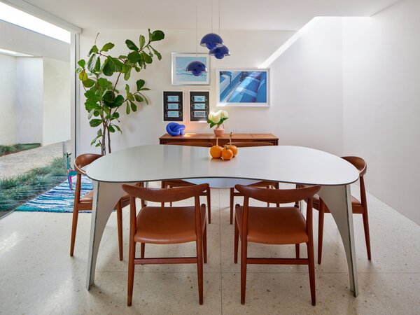 In a recent home makeover, Dan Brunn Architecture based out of Los Angeles, California, gave this midcentury-modern home a playful yet elegant upgrade. Brunn added a skylight, which offers more natural light that enhances the blue tones throughout the dining room. When it comes to style, adding quirky design and color gives this dining room a personality—especially with the intriguing dining set with a curvy tabletop and warm-hued chairs.