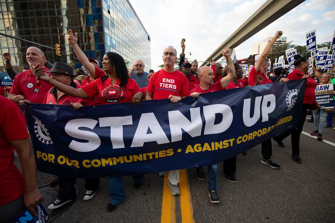 People in red union t-shirts carry a Stand Up sign as they march throughout downtown Detroit.