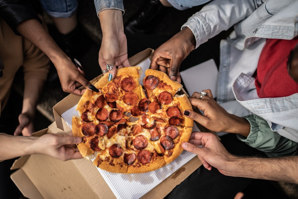 Hands picking pizza slices