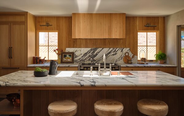 Set below expansive skylights, the kitchen features Italian Calacatta marble counters, a shiplap backsplash and hood wrap, and custom Oak cabinetry.