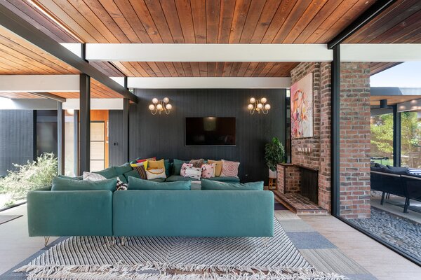 Outside of wonderful natural lighting, the living room is warmly lit by antique wall sconces and a large brick fireplace.