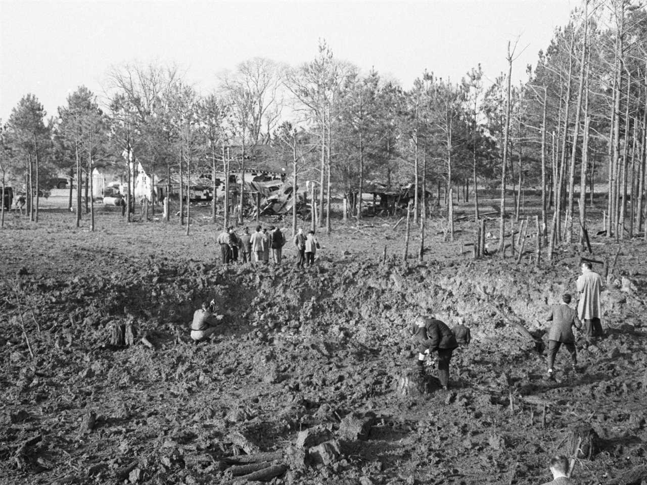 Several people stand around a large crater on a family farm in South Carolina after a B-47 accidentally dropped a bomb in the 1950s