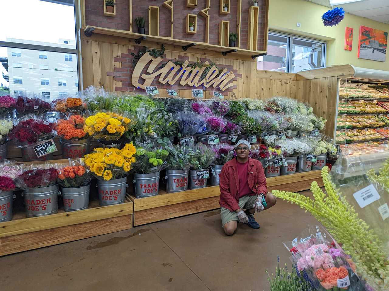 a man crouching in front of the flowers at Trader Joe's