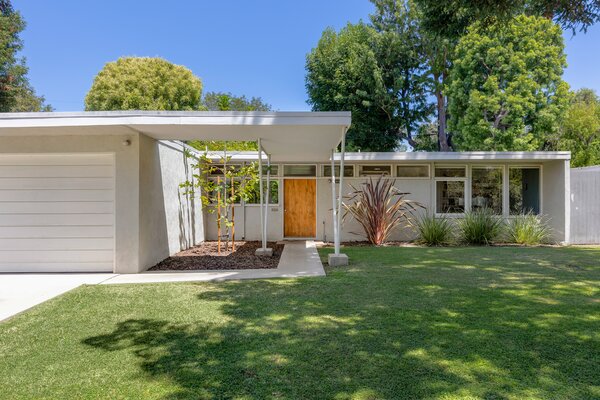 The historic home is surrounded by mature landscaping, including a giant redwood that appears to be about seventy years old. A covered walkway leads to the main entrance.