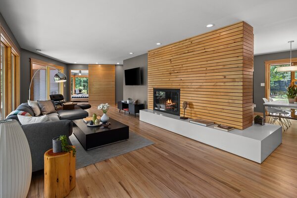 The reclaimed alder-clad, double-fireplace demarcates the open living room and kitchen.