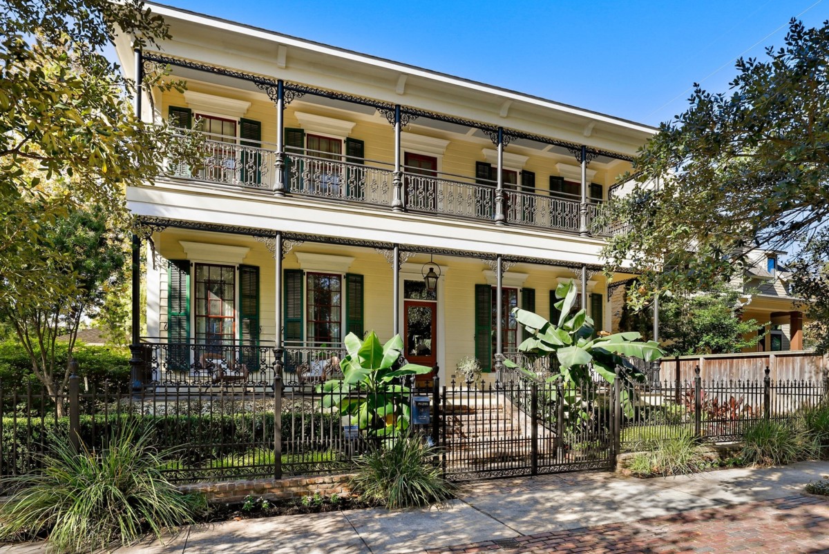 yellow historic looking home in houston with many windows and a balcony