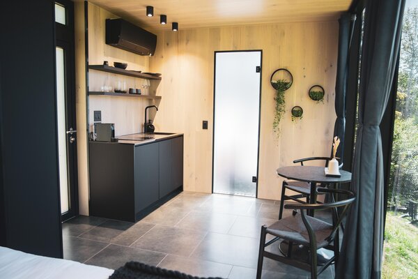 The interior features heated floors alongside a kitchenette, dining area, and bedroom.