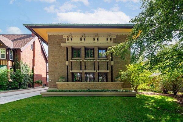 The home's overhanging roof is trimmed with copper, adding a subtle pop of color against its otherwise neutral, brick-clad facade.