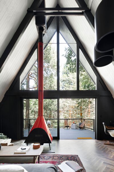 The main living area is anchored by the original fireplace, which now pops against the black and dark gray walls and ceilings. Sliding glass doors invites crisp, fresh mountain air inside.